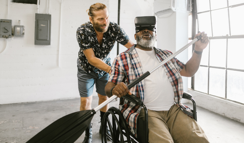 VR Training Solutions: A man on a wheelchair with VR headsets on, is rowing a boat.