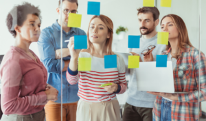 Diverse team collaborating with sticky notes on a board representing effective prosci change management through collaboration and strategic planning