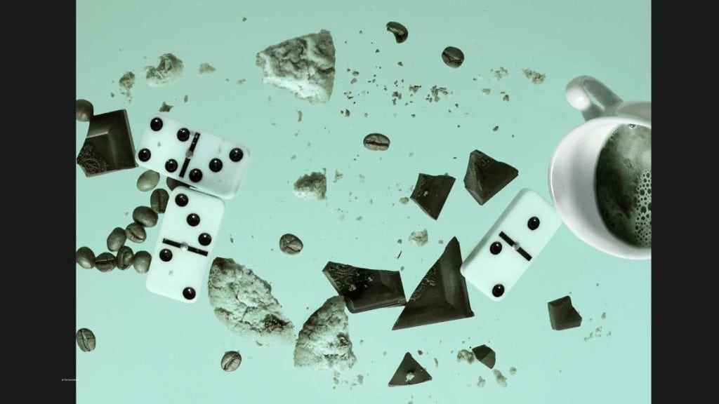 Falling dominoes, coffee, cookies, and chocolate symbolising how one small risk can trigger a chain reaction in business and take you through what an example of a risk management strategy is.