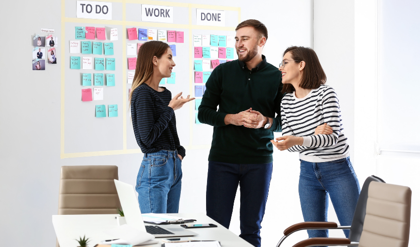 Young business people talking near a Kanban board in the office