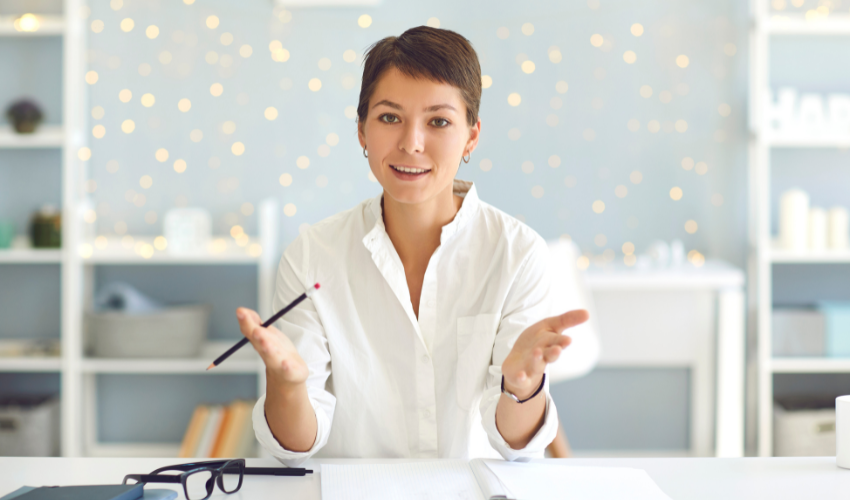 A person at a desk speaking and looking at the camera