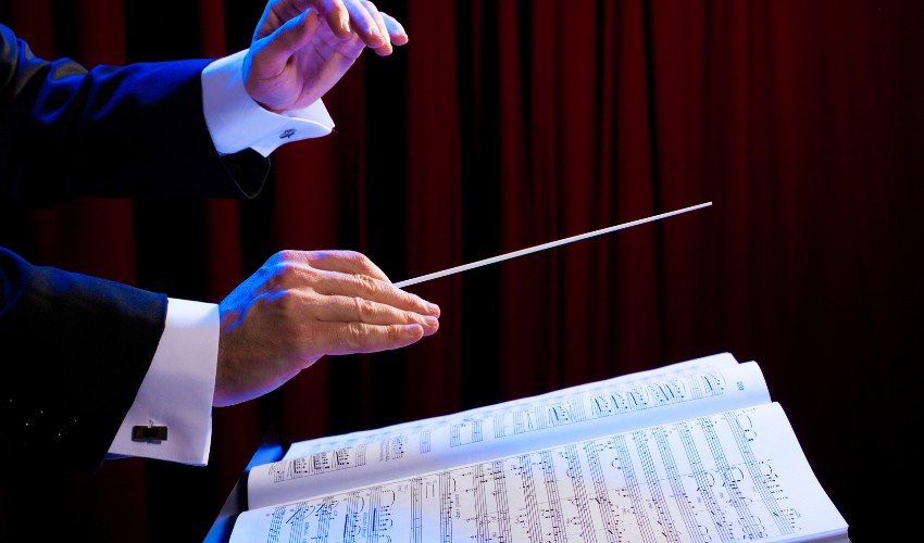 A conductor's hand with a baton over a musical score, illustrating the role of a project manager orchestrating different elements to create harmony.