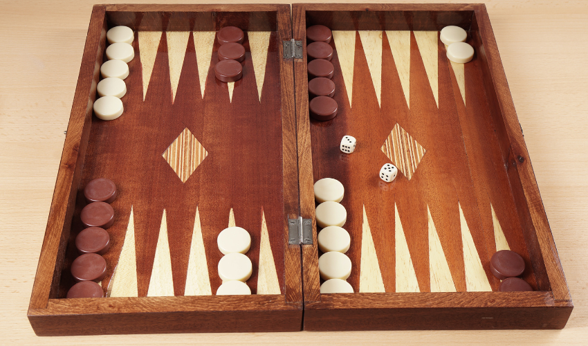 Backgammon board with pieces and dice representing the strategic and calculated nature of embracing risk management for project success.