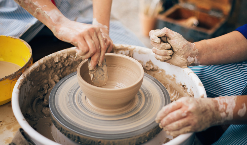 Hands carefully molding clay on a potter’s wheel, depicting the crafting and executing phases of a change management plan."